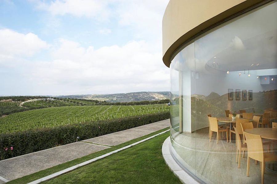 one side of the building with green lawn of Boutari Crete Winery next to the vineyards